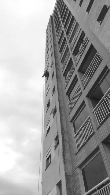 Alpinista em fachada de edifício