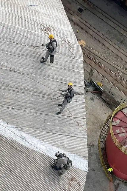 Equipe de alpinistas em cobertura industrial