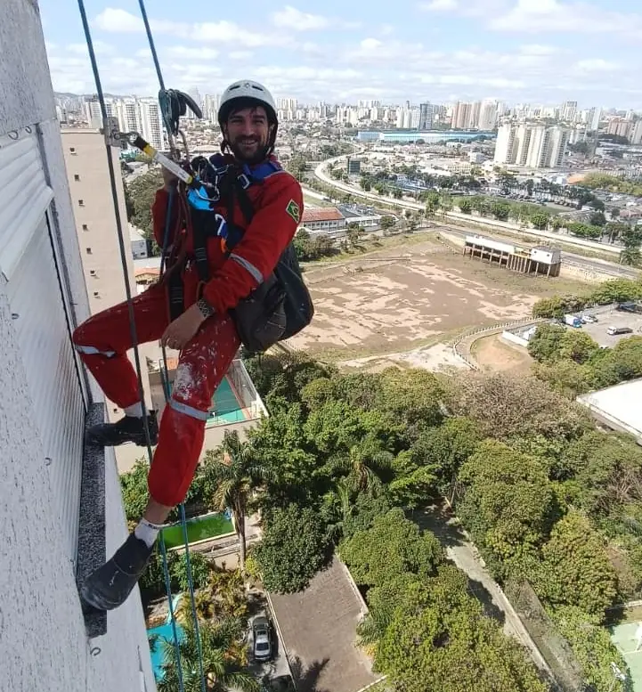 Técnico em acesso por cordas equipado com EPIs em fachada